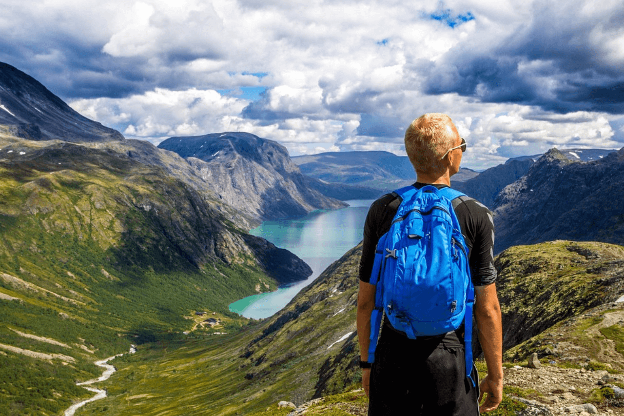 Man looking out into a valley wearing a bright blue backpack