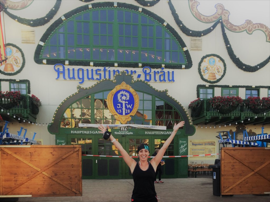 Woman in athletic gear standing with her arms raised at oktoberfest 