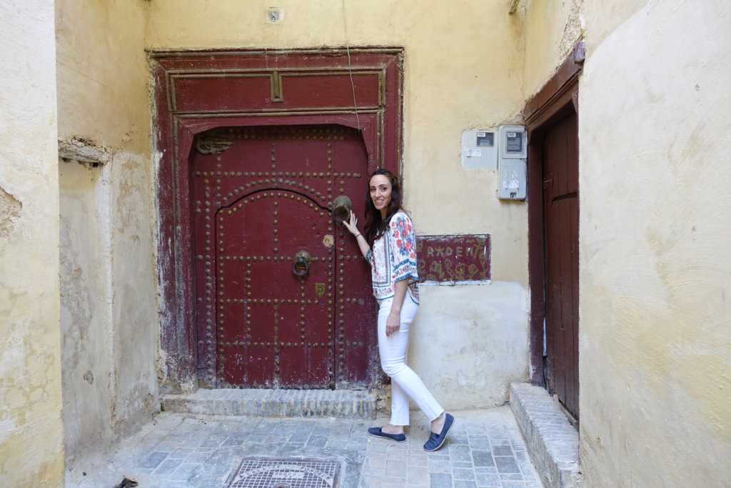 Woman standing in front of a brown doorway in Meknes Morocco 