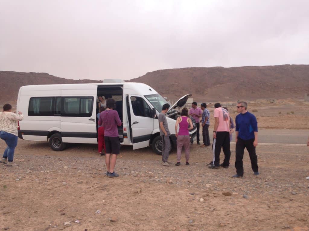 White Van with hood open and people standing around it 