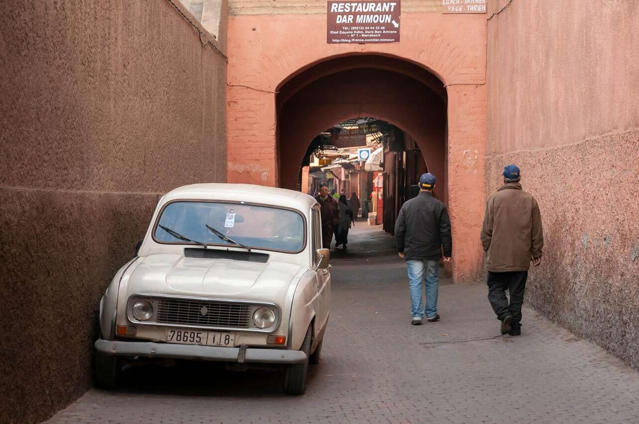 unrecognizable men walking on street near arched passage