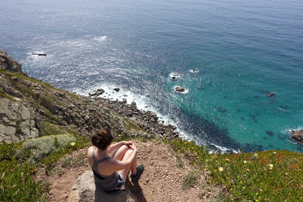 Gina sitting on a cliff looking at the Atlantic Ocean in Portugal