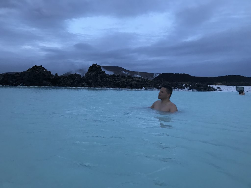 Man relaxing in blue water with mountains in background