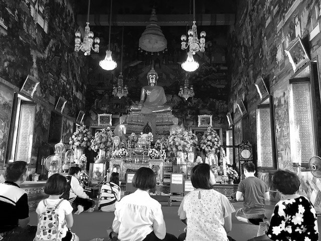 People sitting on the floor of a temple in thailand