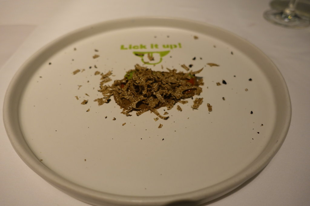 Pile of herbs on a white plate with Lick it up written on it