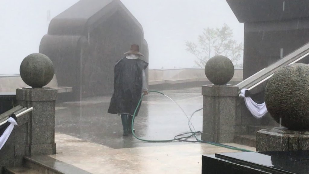 Man hosing the ground in a monsoon