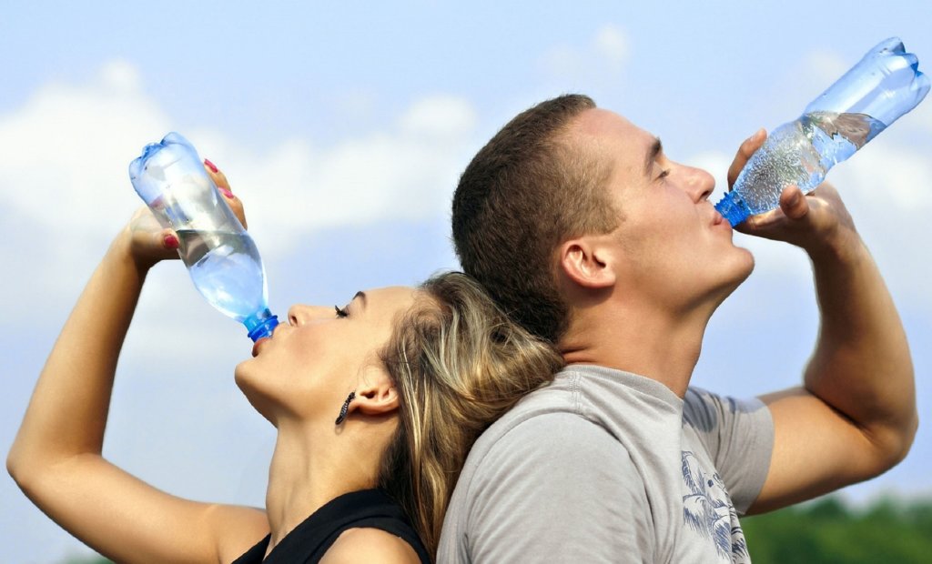 Two people drinking water from plastic bottles