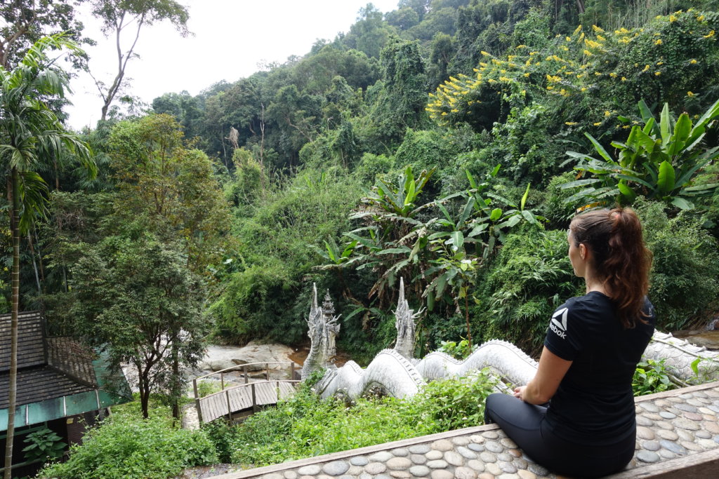Gina sitting on a bench at a temple in a short sleeve shift to show you what runners pack when traveling