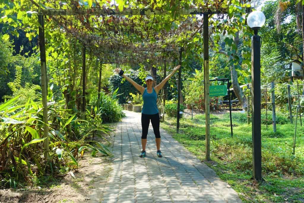 Gina standing in a garden with her hands up 