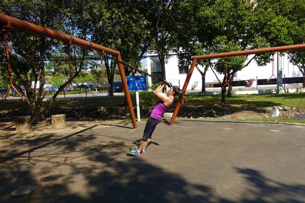 Gina using a TRX strap in a park 