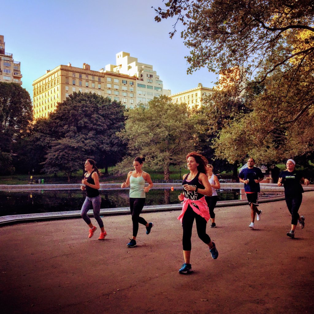 A group of woman running near the conservatory pond in central park with Fit Tours