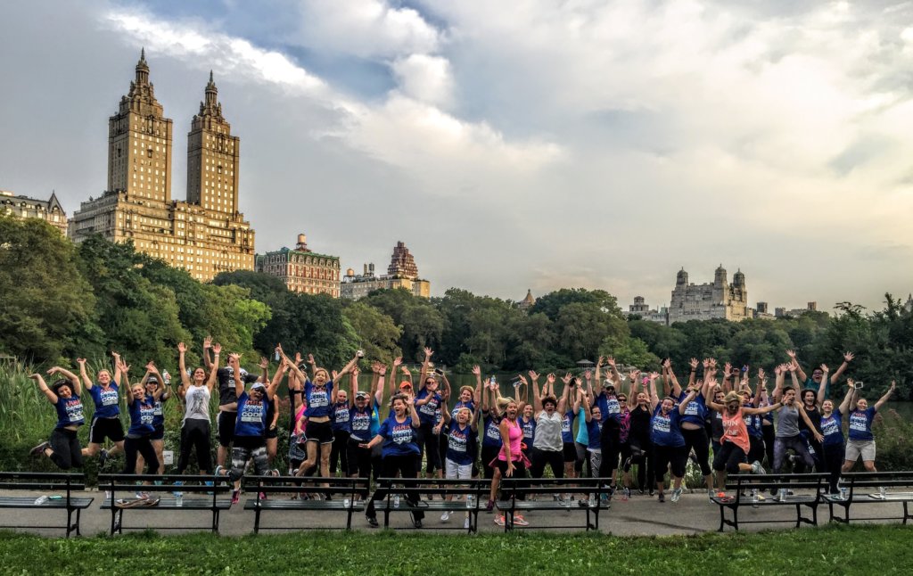 A large group of people jumping near a lake on the best running tour in NYC