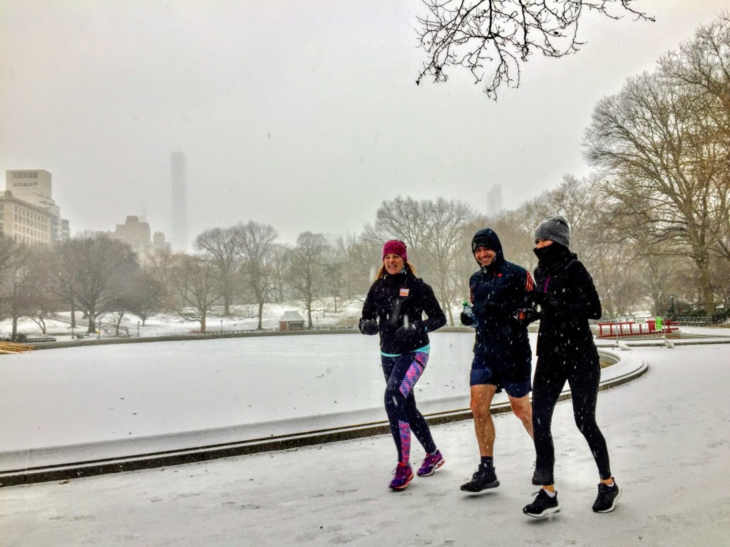 Three people running in the snow in central park