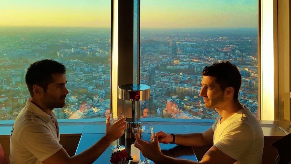 Two men sitting at a table clinking glasses in a Berlin restaurant 