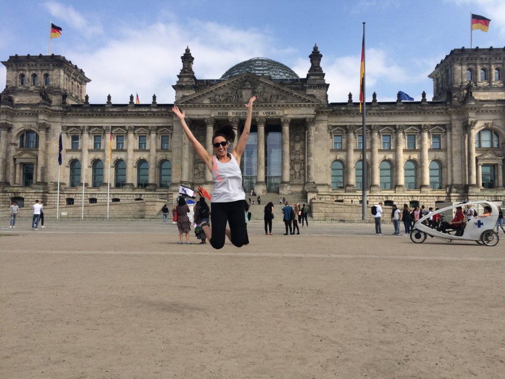 A woman jumping in front of a Berlin building 