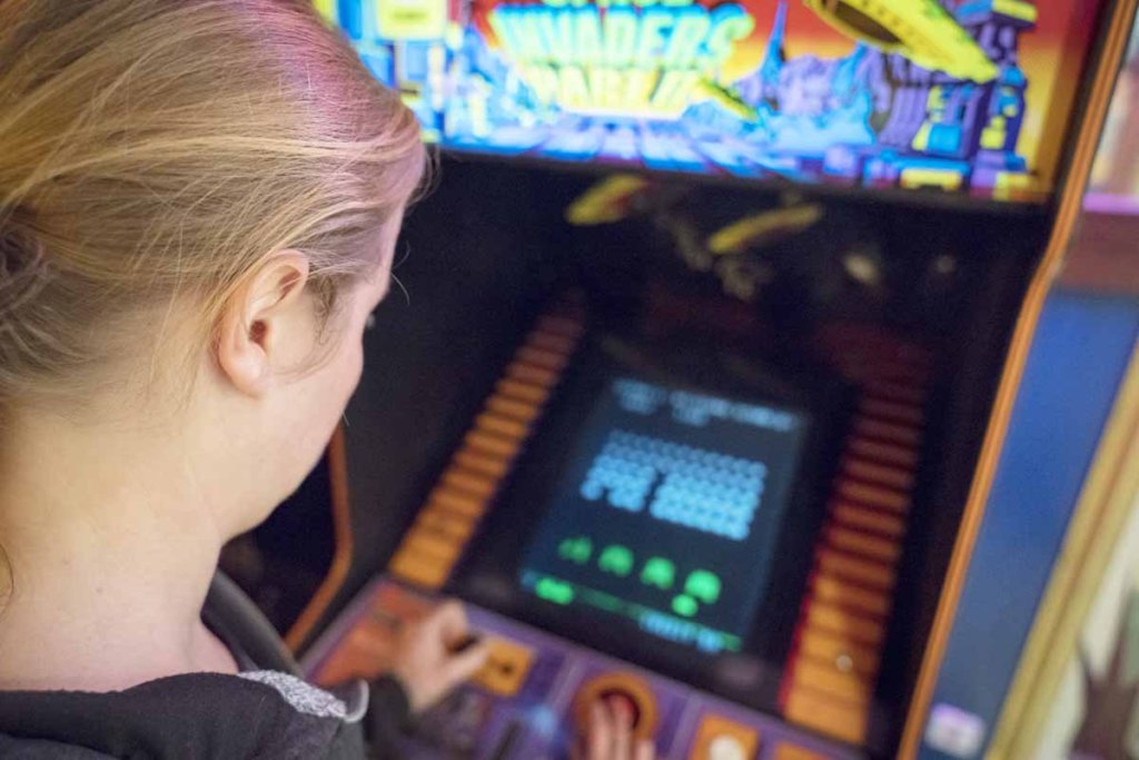 A woman playing an old arcade game 