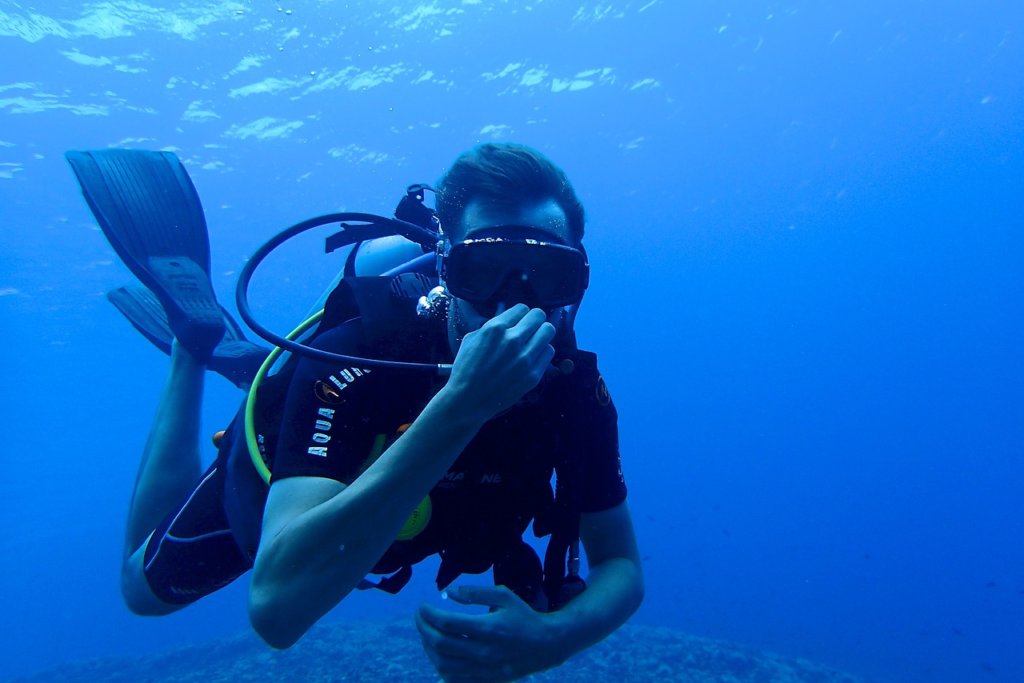 A man holding his nose underwater diving
