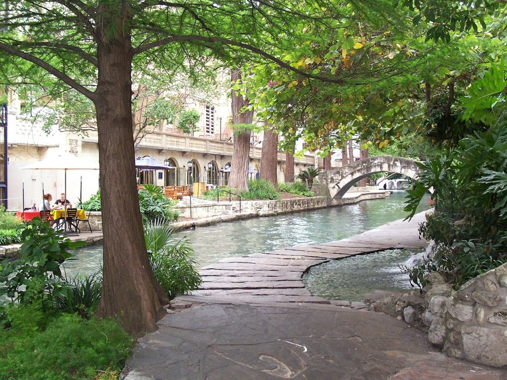 A concrete walkway along a river lined with trees in San Antonio 