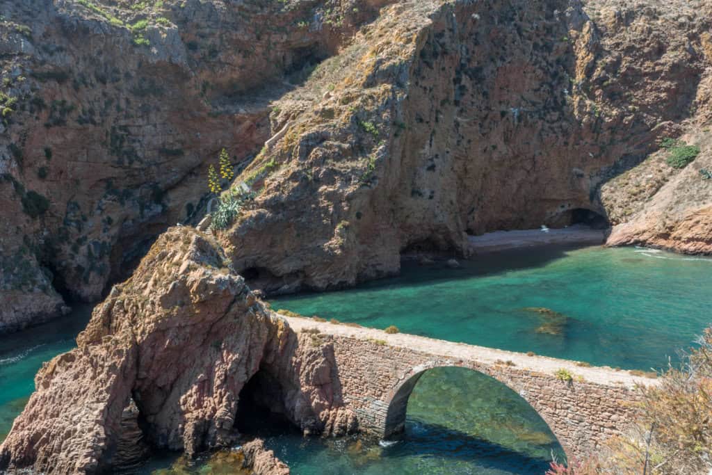 A white stone archway in blue and green water as one of the best day trips from lisbon 