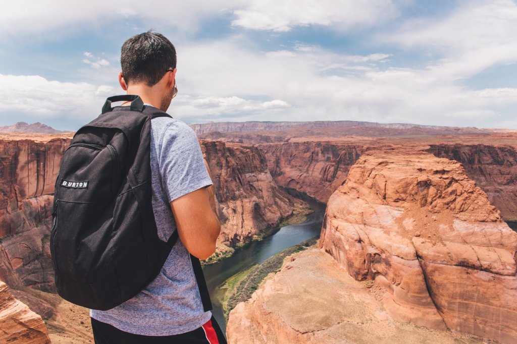 a man with a backpack looking at the grand canyon