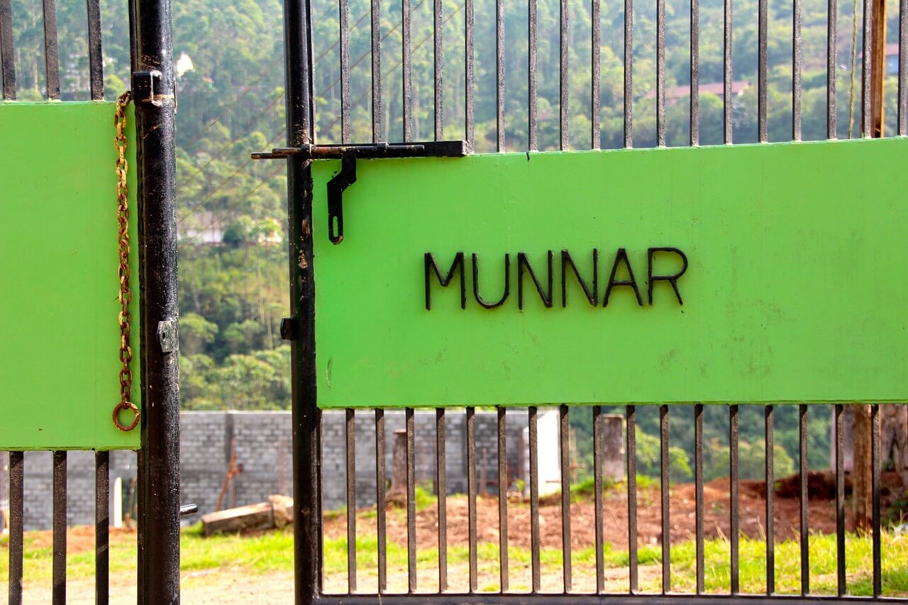 a green sign thats says Munnar on a fence