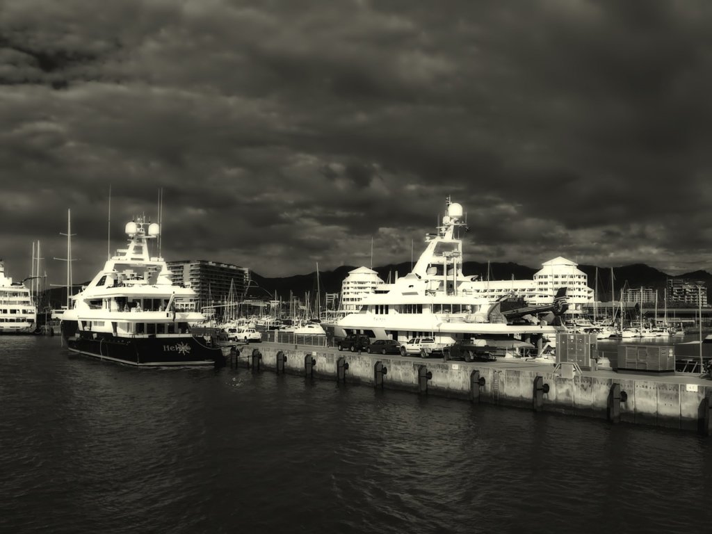 A block and white image of two boats at a dock in Cairns