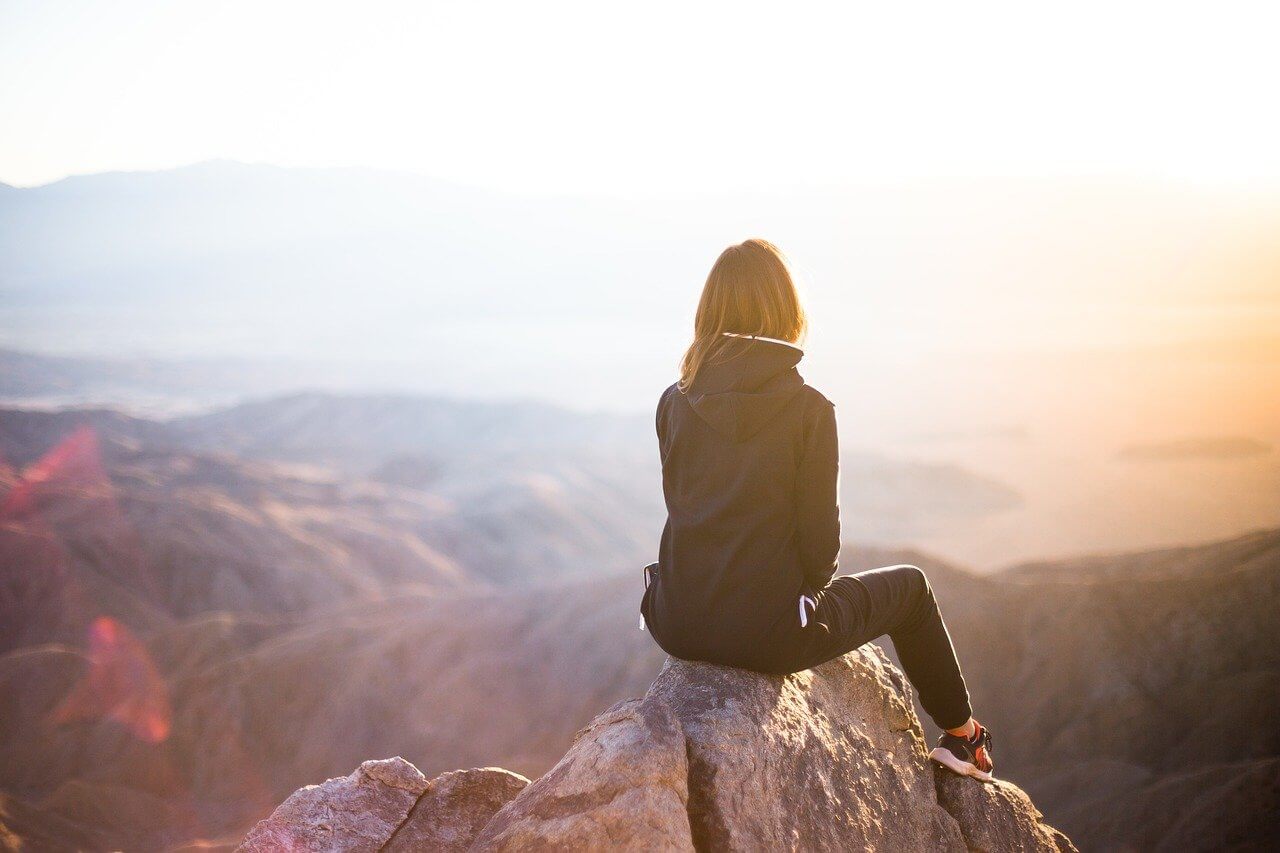 Woman sitting on a cliff relaxing sunset