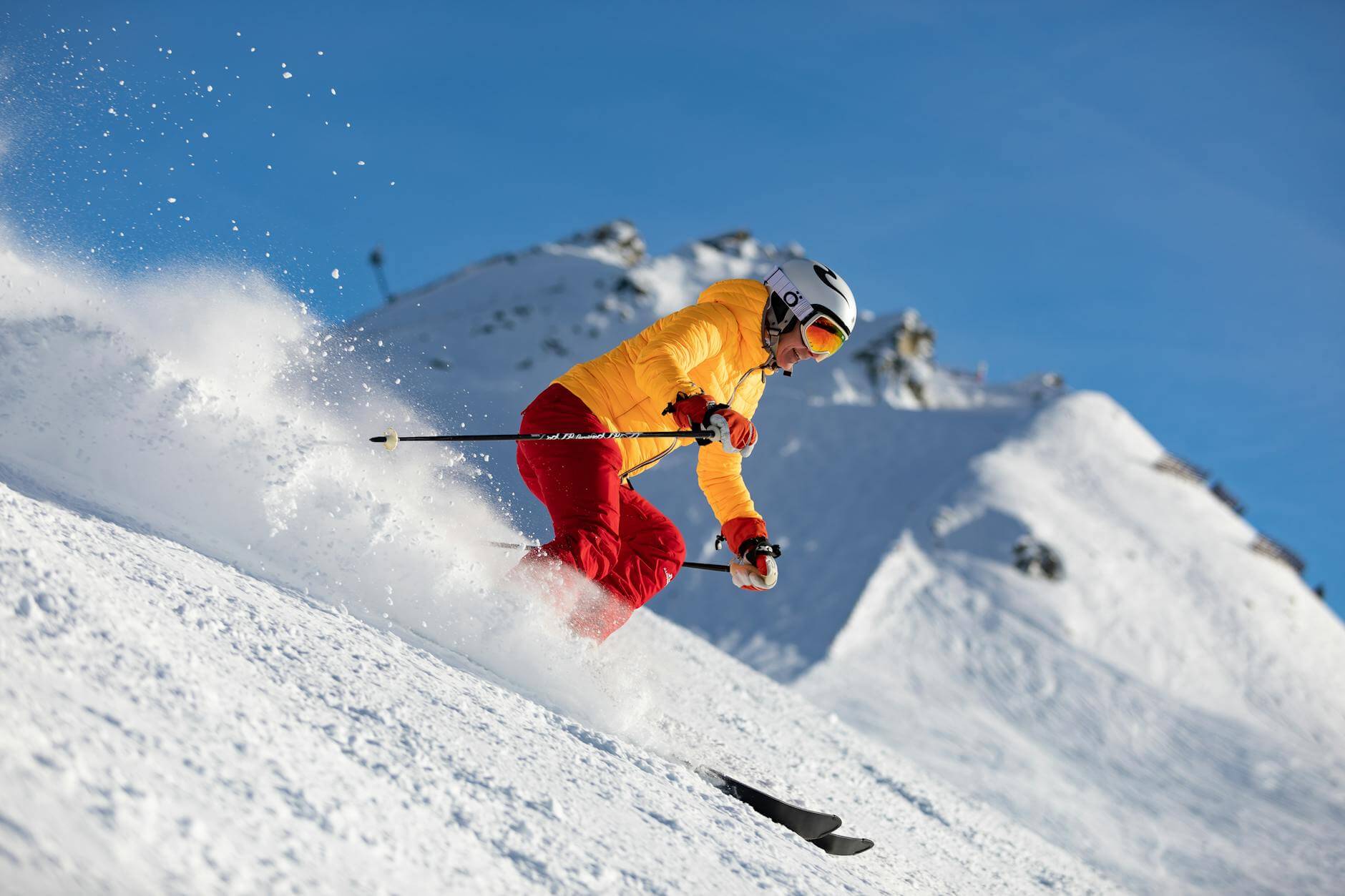 person in yellow jacket and red pants skiing