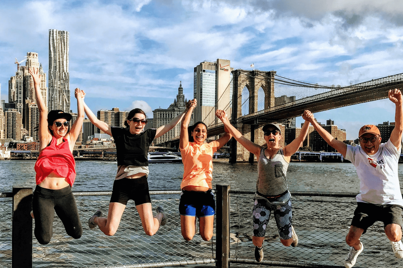 Group of runners jumping in front of the brooklyn bridge on a fun NYC tour