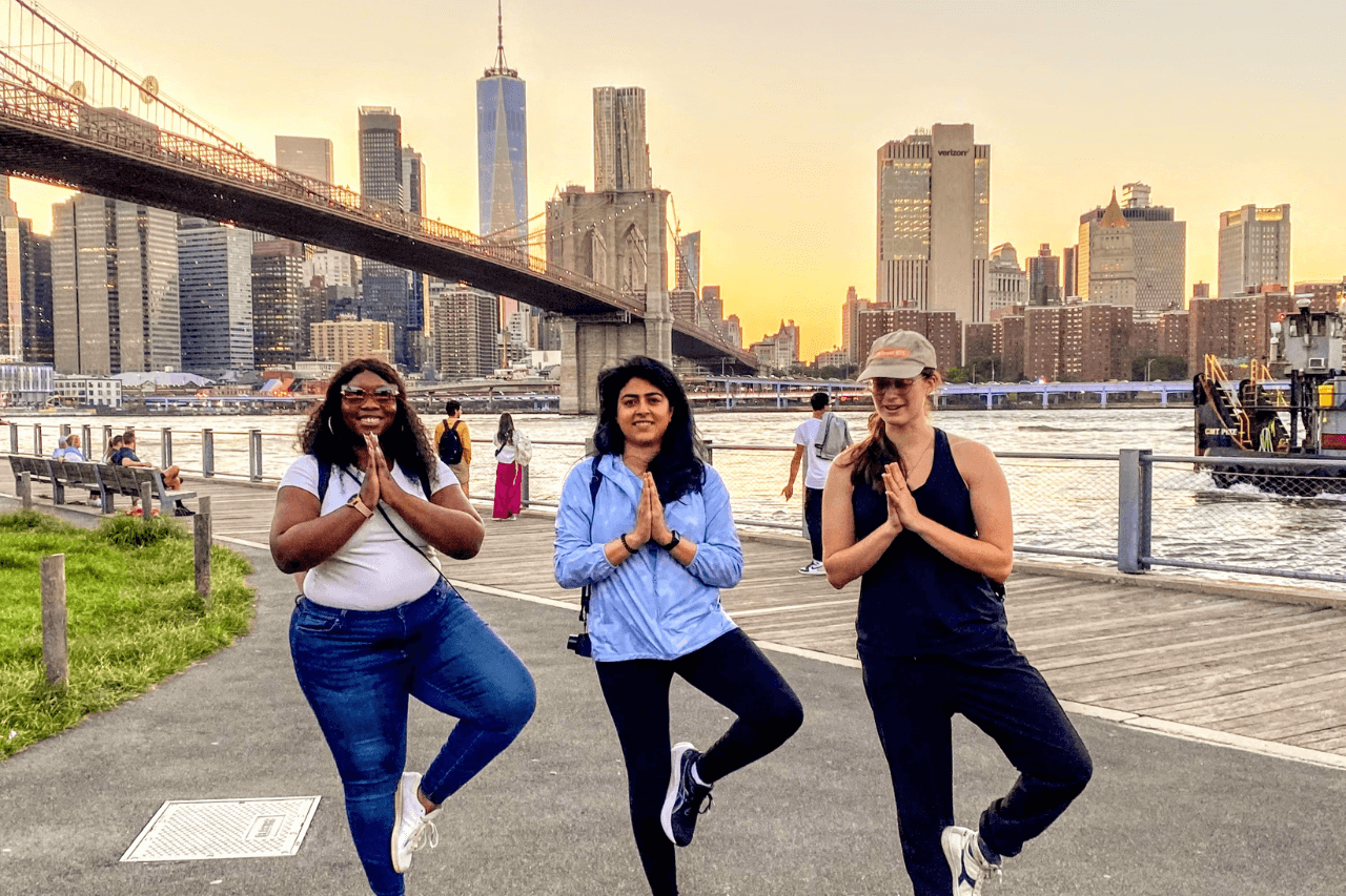 Three woman doing yoga with a NYC skyline