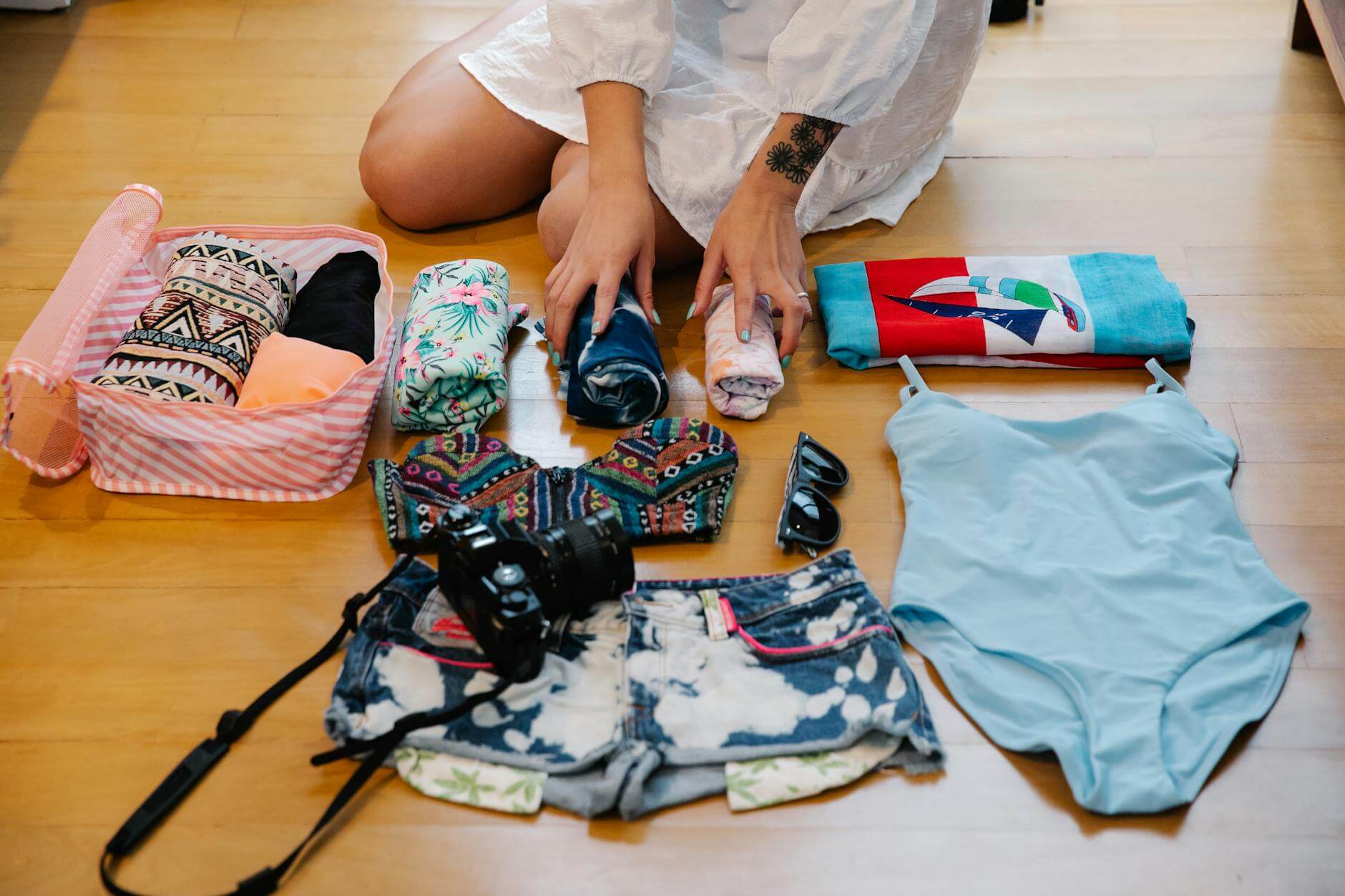 a person sitting on a wooden floor while preparing travel essentials for her florida packing list