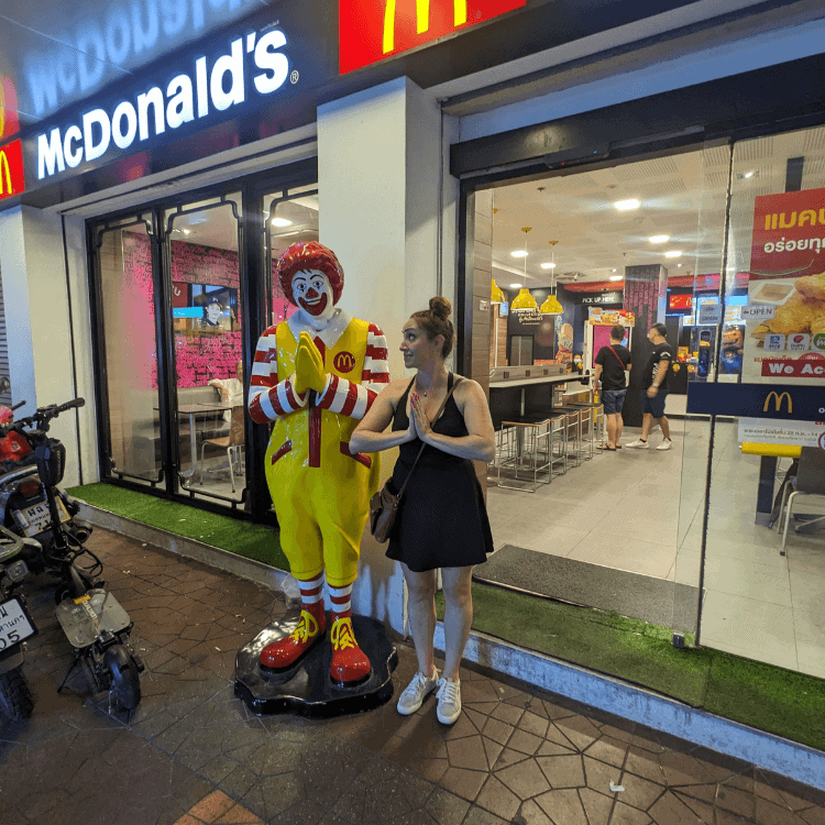 woman with hands in prayer next to mcdonalds on khao san road