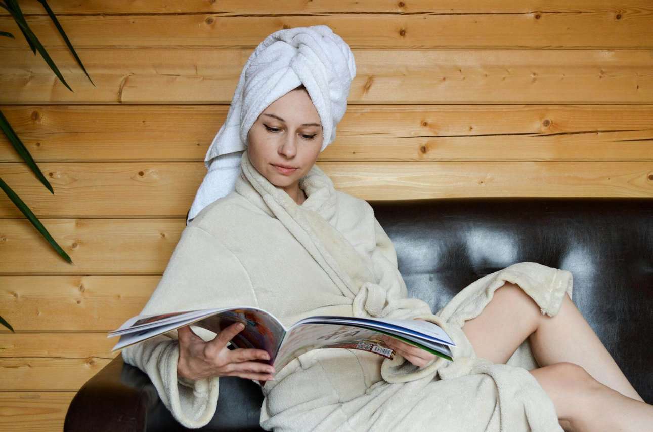 focused woman reading magazine in sauna