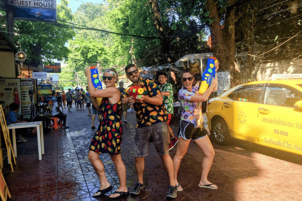 three people holding water guns at songkran on khao san road