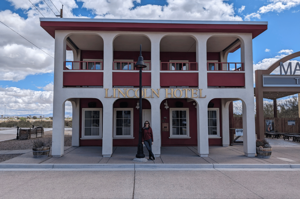 woman standing in boom town in front of the lincoln hotel replica