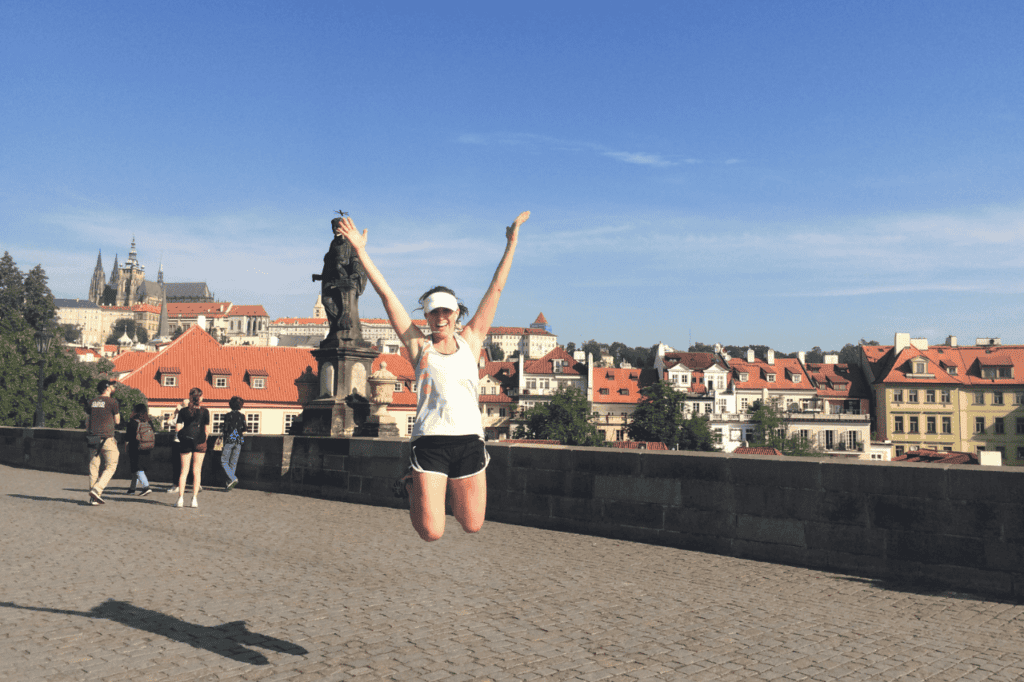 woman jumping up after running a bridge in prague