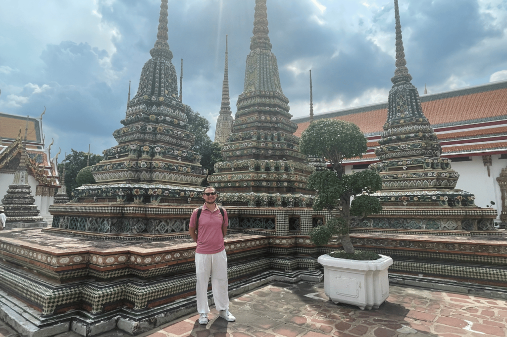 man standing in front of a sculpture at grand palace