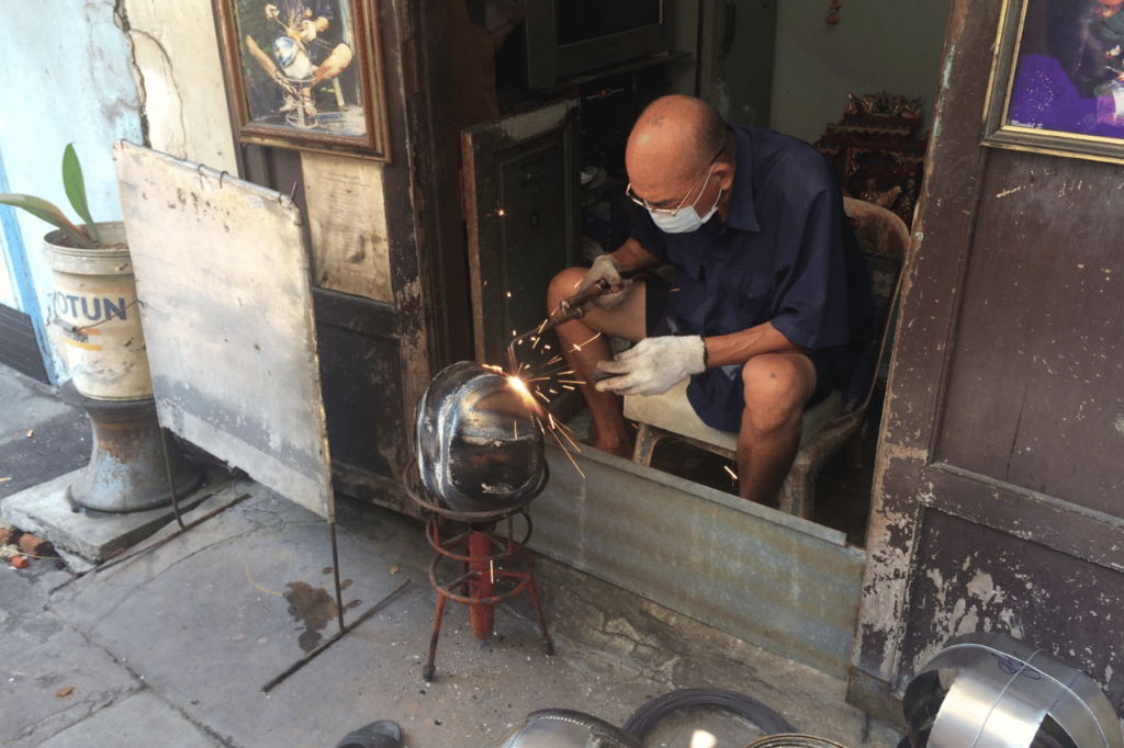 man working on a metal helmet in bangkok on a 4 day bangkok itinerary tour 