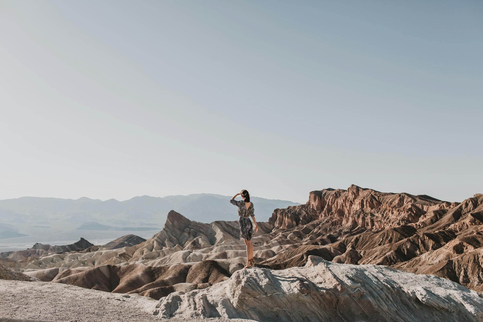 back view shot of a woman standing on a rocky mountain hiking in death valley 
