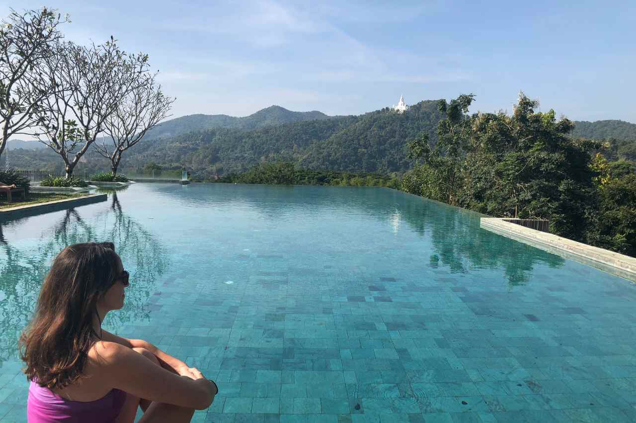 woman sitting next to a blue pool at a wellness retreat