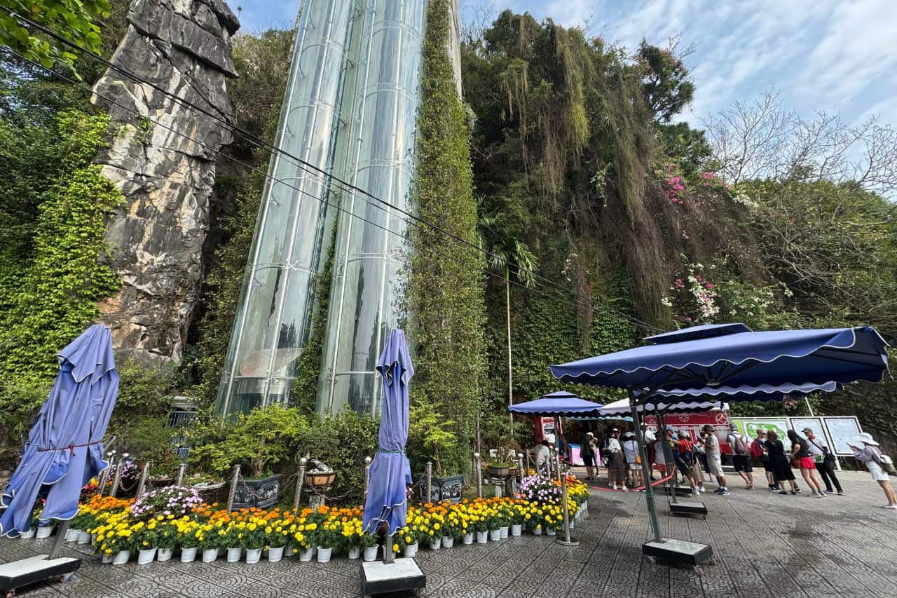 Elevator Entrance at Marble Mountains Vietnam Glass elevator shafts surrounded by greenery and tourists at the base of Marble Mountains Vietnam