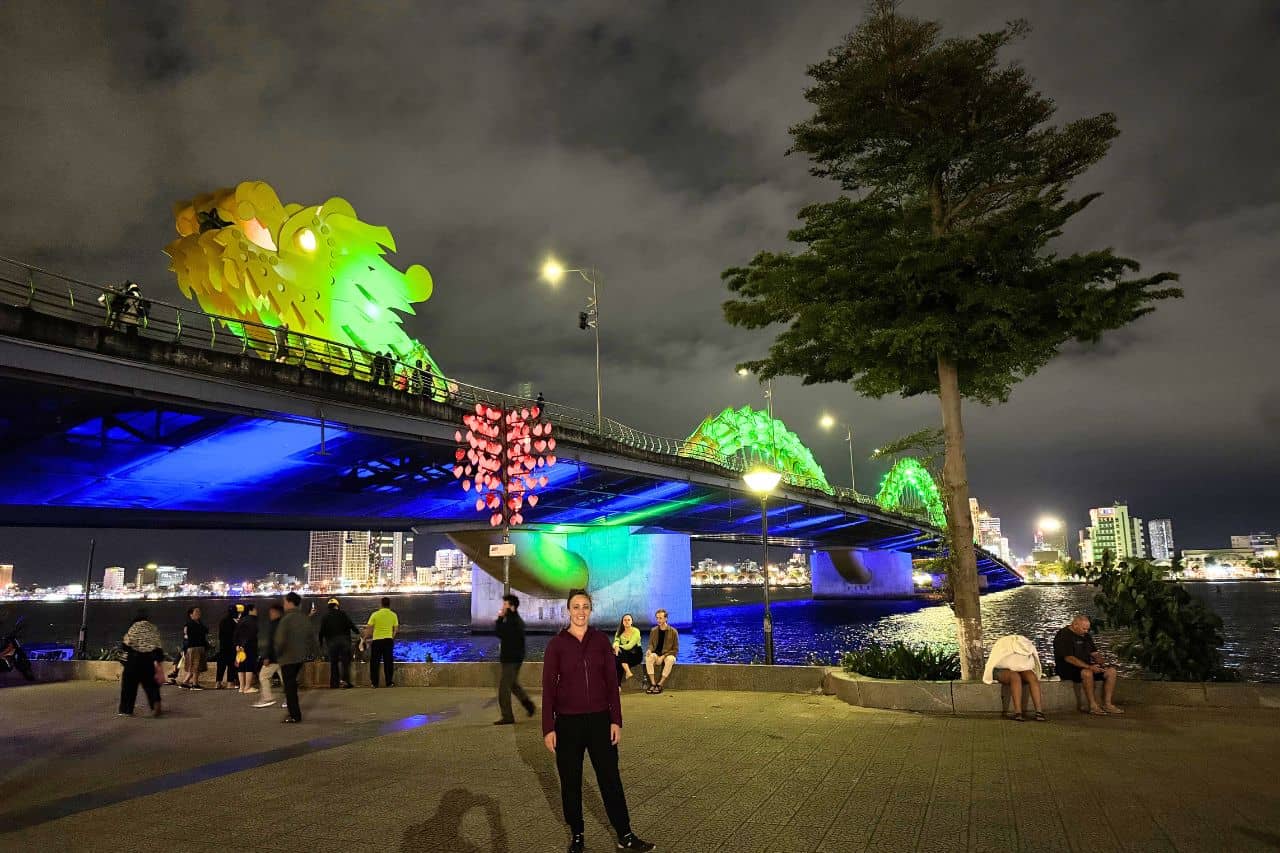 Dragon Bridge in Da Nang Lit Up at Night The iconic Dragon Bridge in Da Nang glowing in green and blue lights with people enjoying riverside views