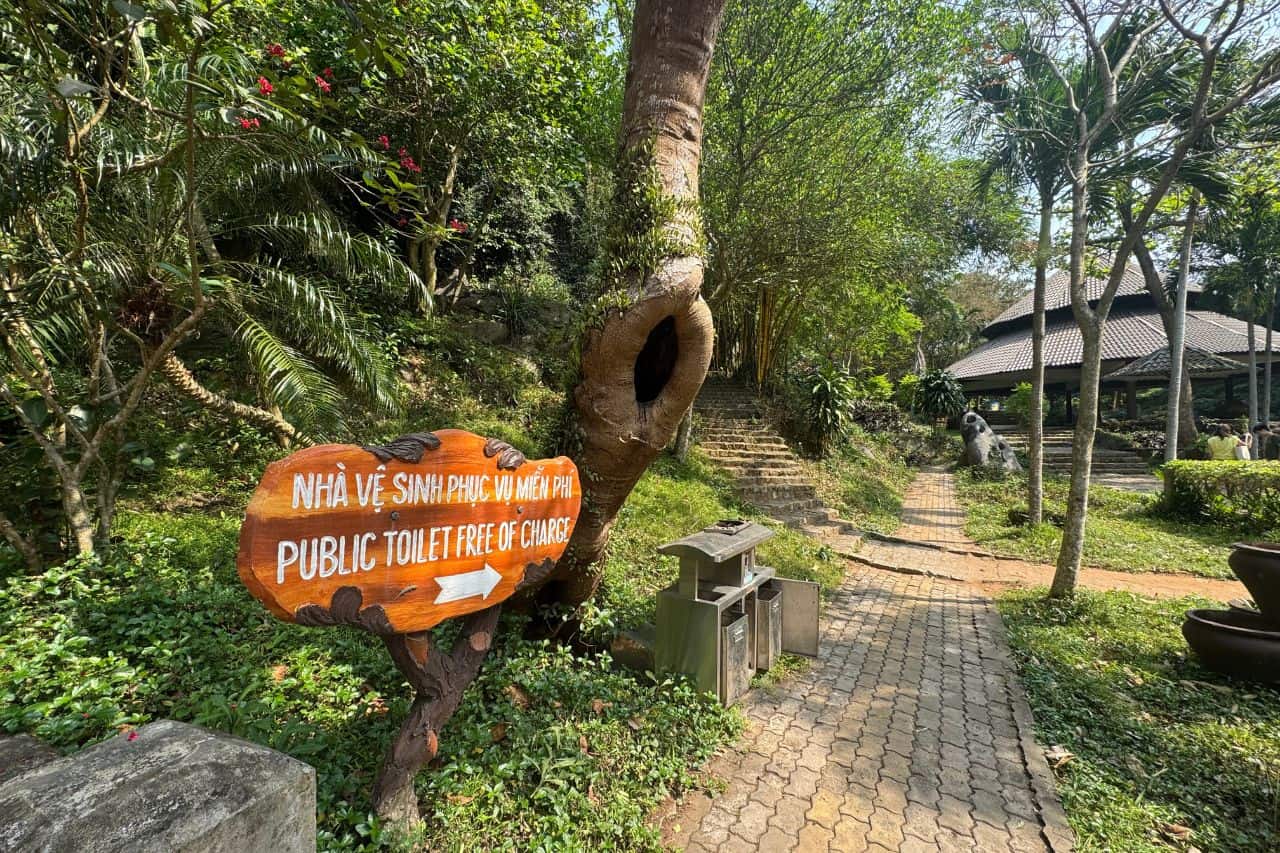 Public Toilet Sign on Garden Path Wooden sign for free public toilets along a leafy path in Marble Mountains Vietnam