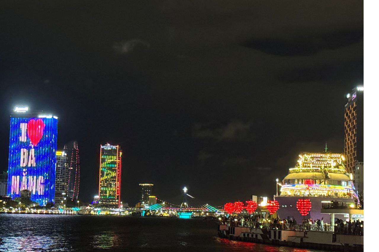 Da Nang Skyline and Cruise at Night Night view of Da Nang skyline with colorful lit buildings and the Love Bridge adorned with red heart lanterns