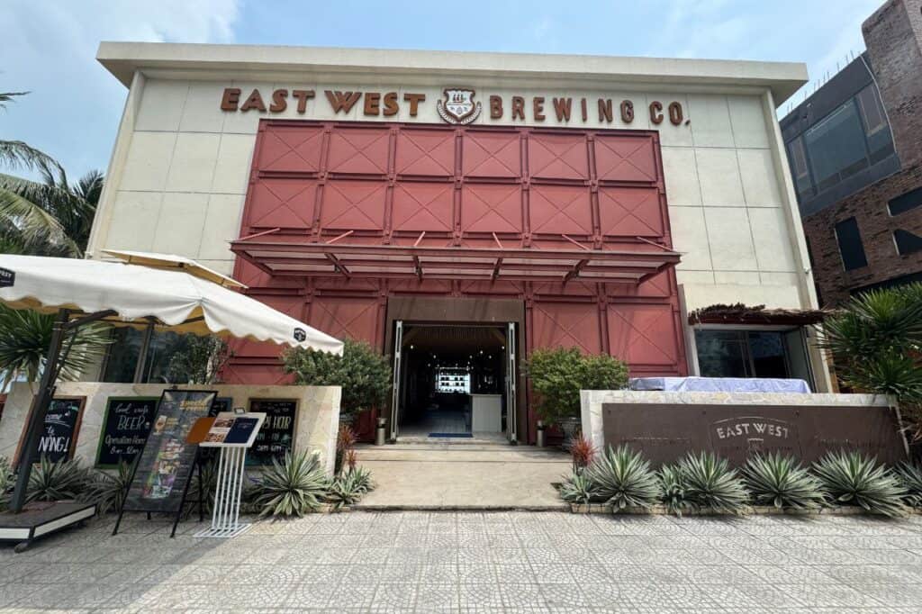 Front view of East West Brewing Co. in Da Nang with red industrial-style doors and outdoor signage