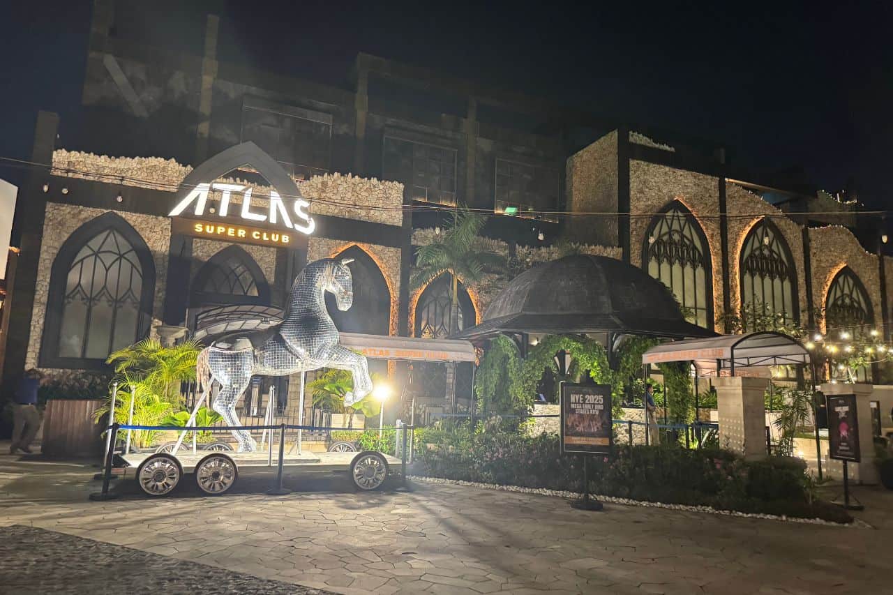 Entrance to Atlas Super Club at Night in Bali Crowded street in Canggu with dozens of scooters and riders navigating through traffic.