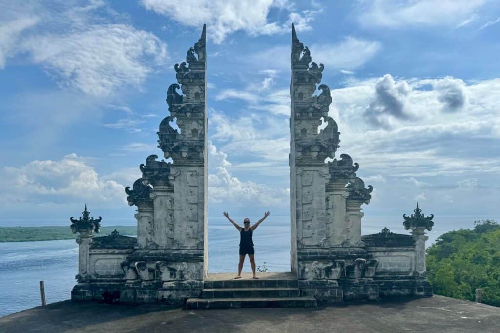 Entrance to a Balinese temple with intricate stone carvings and statues, featuring a split gate design.