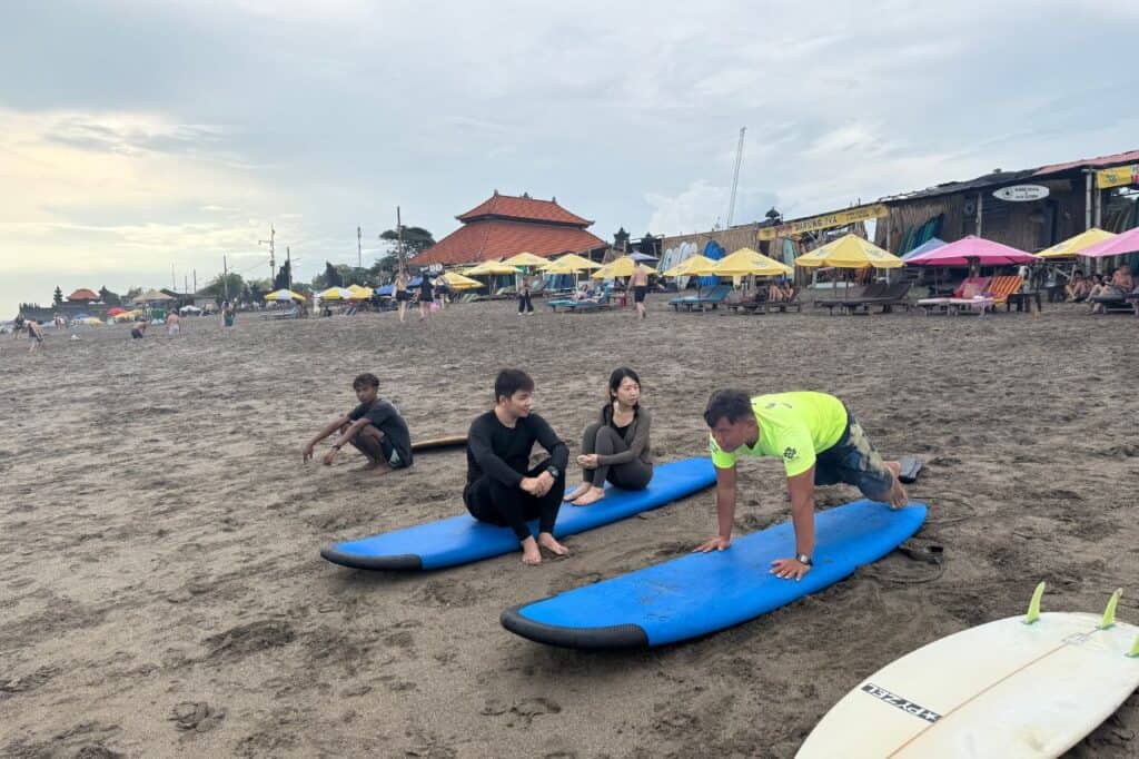 Surf instructor giving lessons on beach in Canggu Bali with students on surfboards