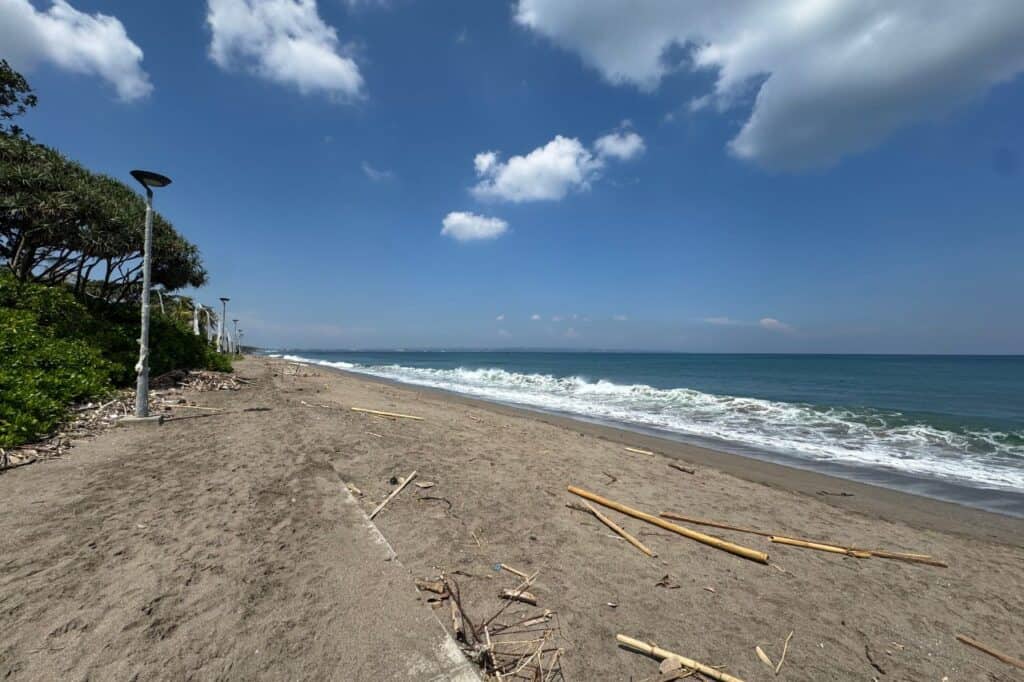 Empty stretch of beach in Canggu Bali with ocean waves and scattered driftwood