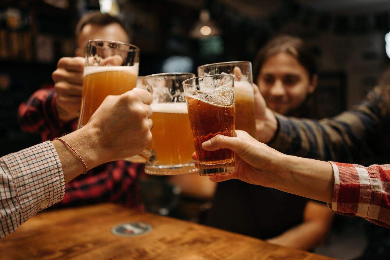 Group of friends clinking beer mugs at a lively bar in Canggu
